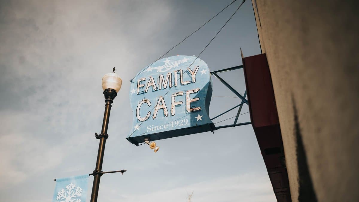 Rustic family cafe sign with charming vintage design and urban backdrop.