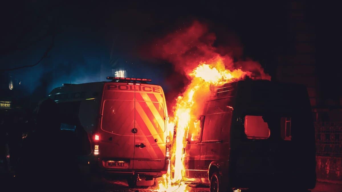 Intense night scene of a van on fire near police vehicles in Bristol, England.