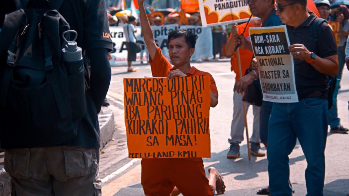 Protesters hold signs criticizing political figures during a street protest.