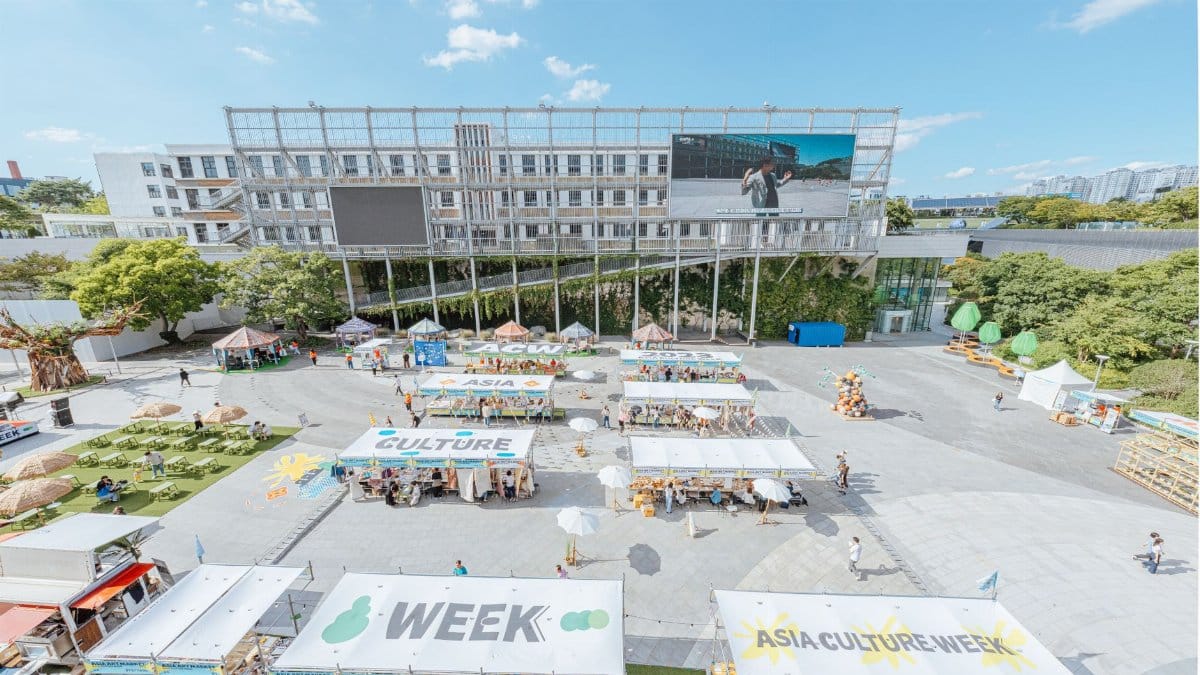 A vibrant outdoor market celebrating Asia Culture Week with stalls and greenery.