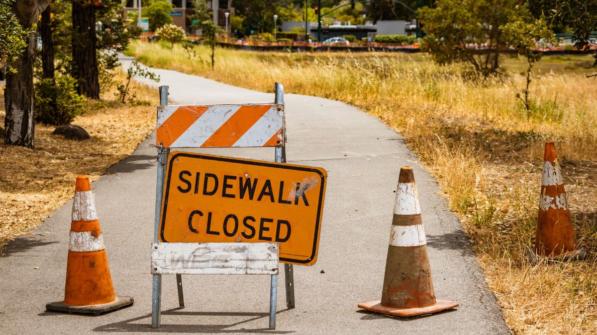 A closed sidewalk with caution sign and cones indicates a maintenance area.