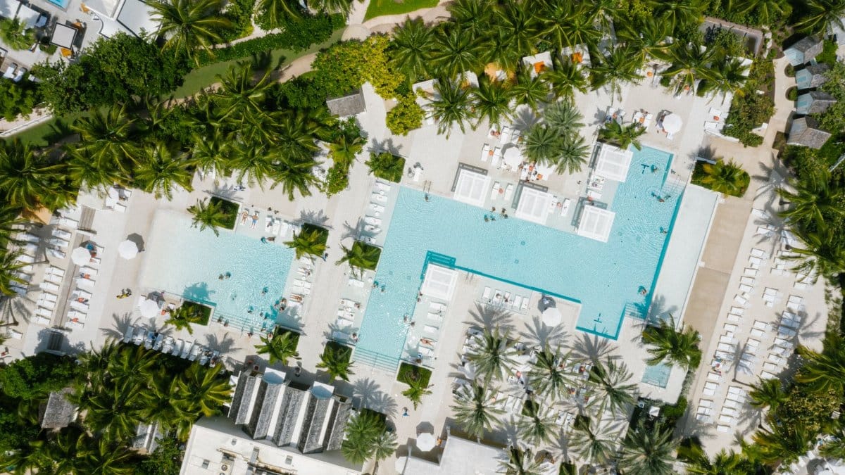 A stunning aerial view of a luxurious resort featuring expansive swimming pools and lush greenery in the Bahamas.