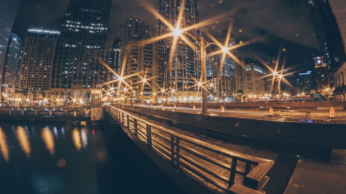 A breathtaking view of a city at night featuring illuminated skyscrapers and a reflective river.