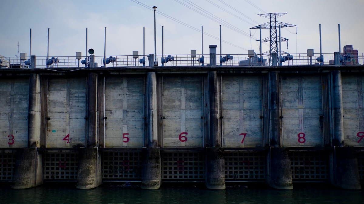 High angle view of an urban dam wall with numbered sections and power lines above.