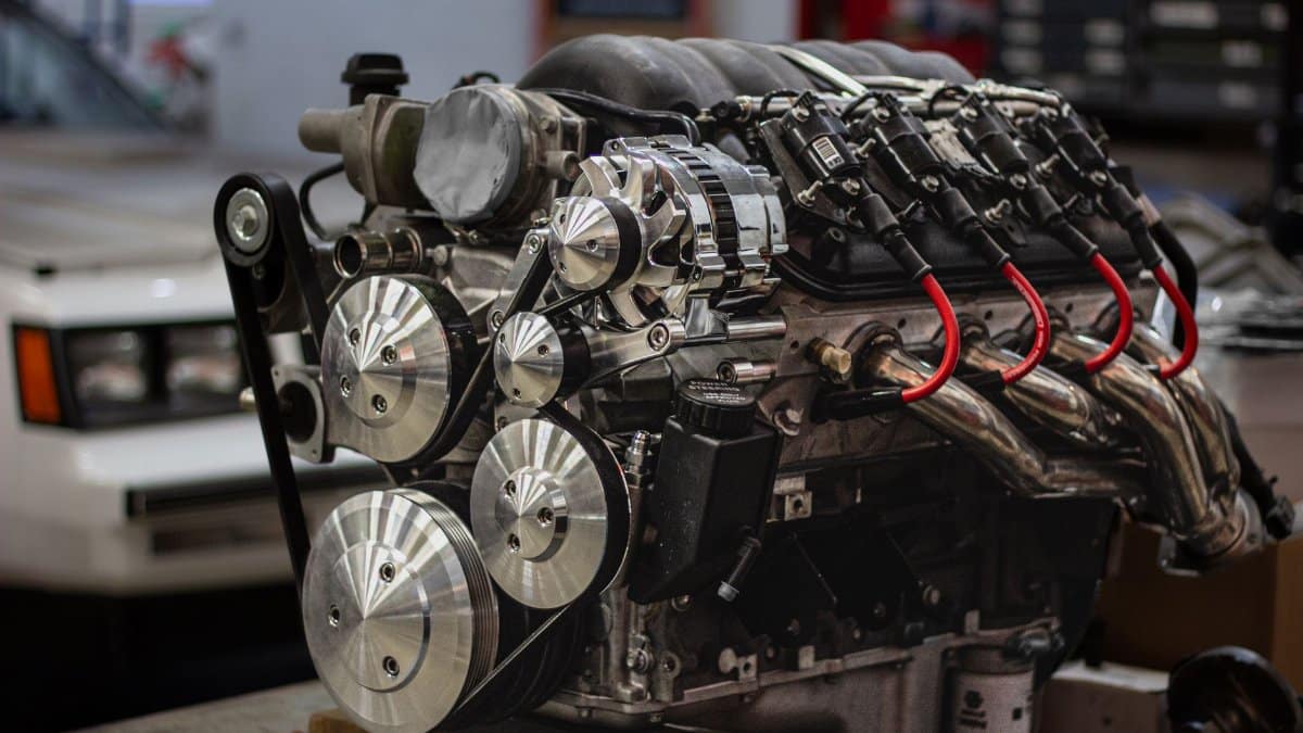 Detailed shot of a powerful car engine in a garage setting, highlighting mechanical components.