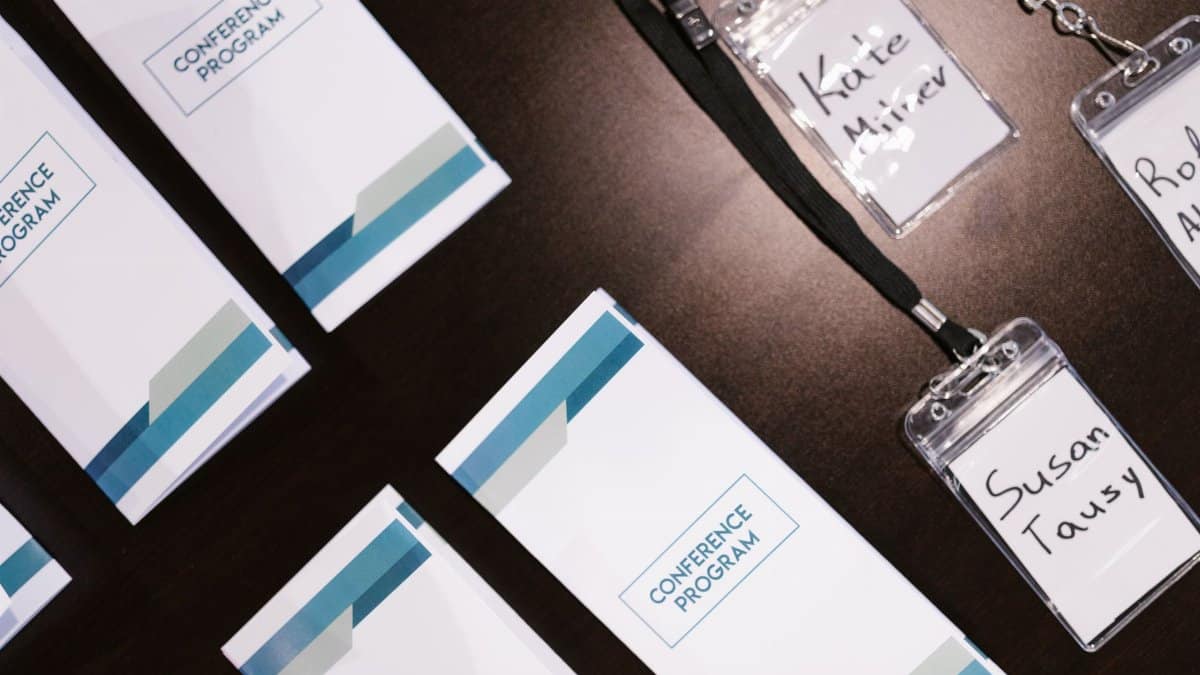 High-angle view of conference programs and name badges on a table, ideal for corporate event visuals.