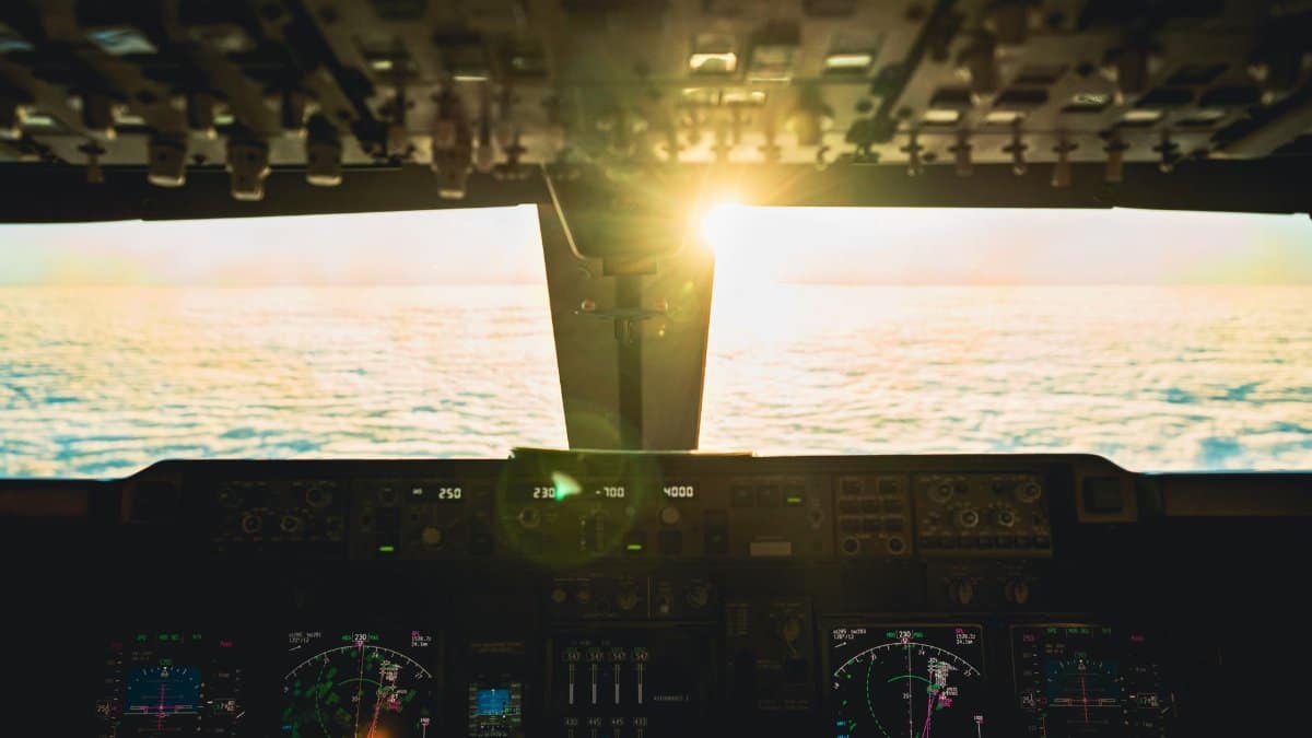 Captivating view from airplane cockpit at sunset over ocean, revealing flight controls.