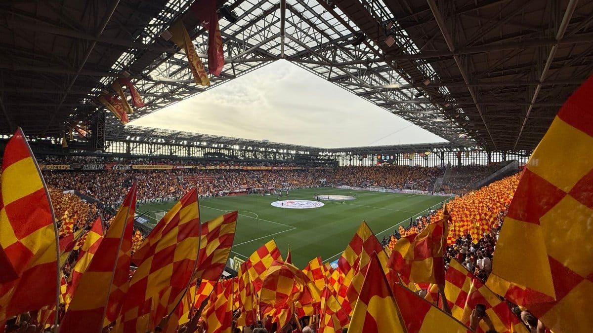 Energetic fans with flags create a lively atmosphere at İzmir football stadium.