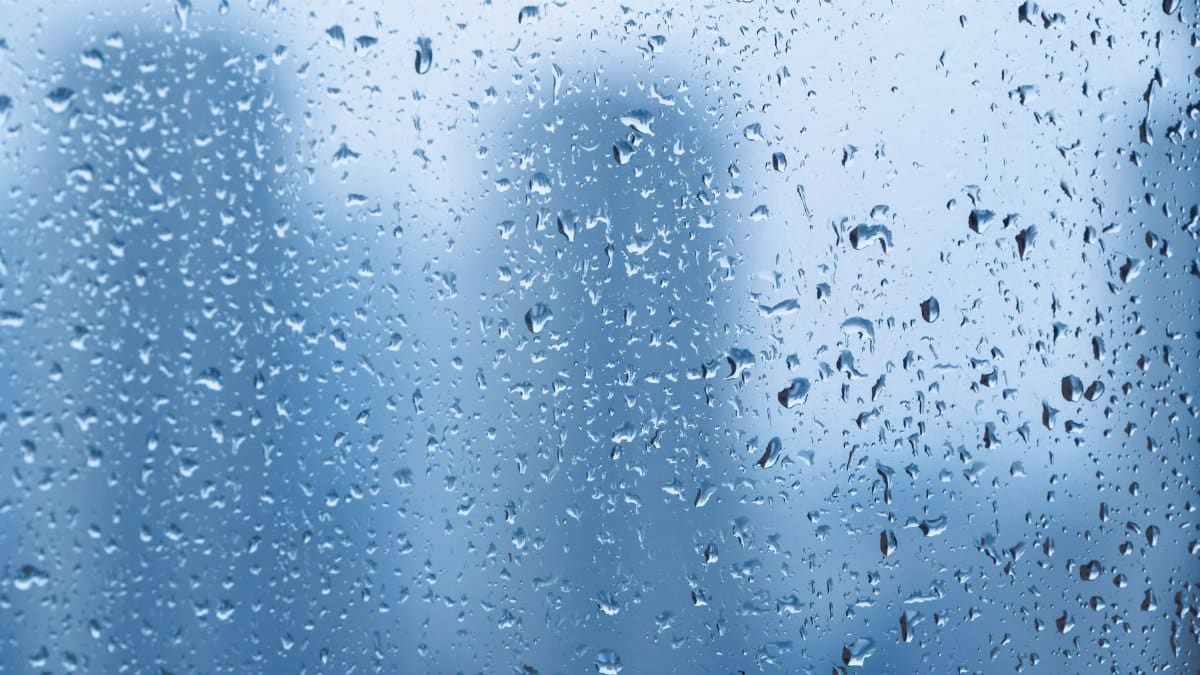 Raindrops on a window with blurred cityscape background creating a tranquil mood.