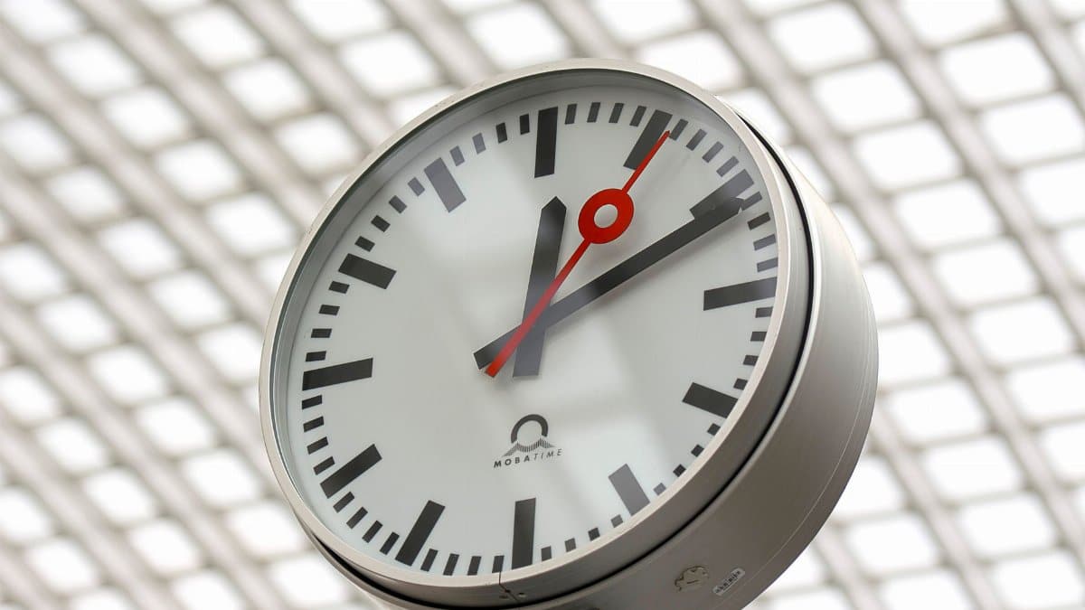 Close-up of a modern analog clock against a geometric background, perfect for time-related themes.