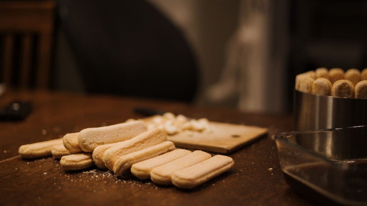 Ladyfingers laid out for a homemade dessert preparation in a cozy kitchen setting.