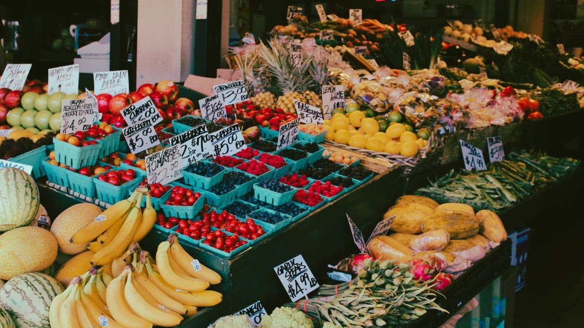 Colorful fruit and vegetable market stall displaying a variety of fresh produce with visible price tags.