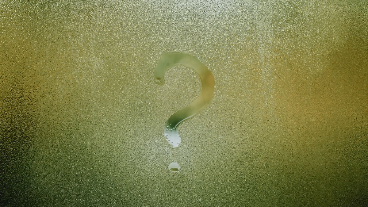 Translucent wet glass window covered with water drops with question mark on surface