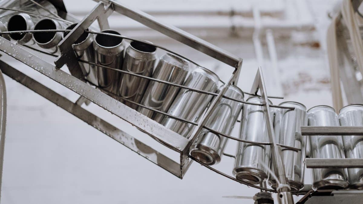 Conveyor belt with empty aluminum cans in a factory setting, showcasing production equipment.