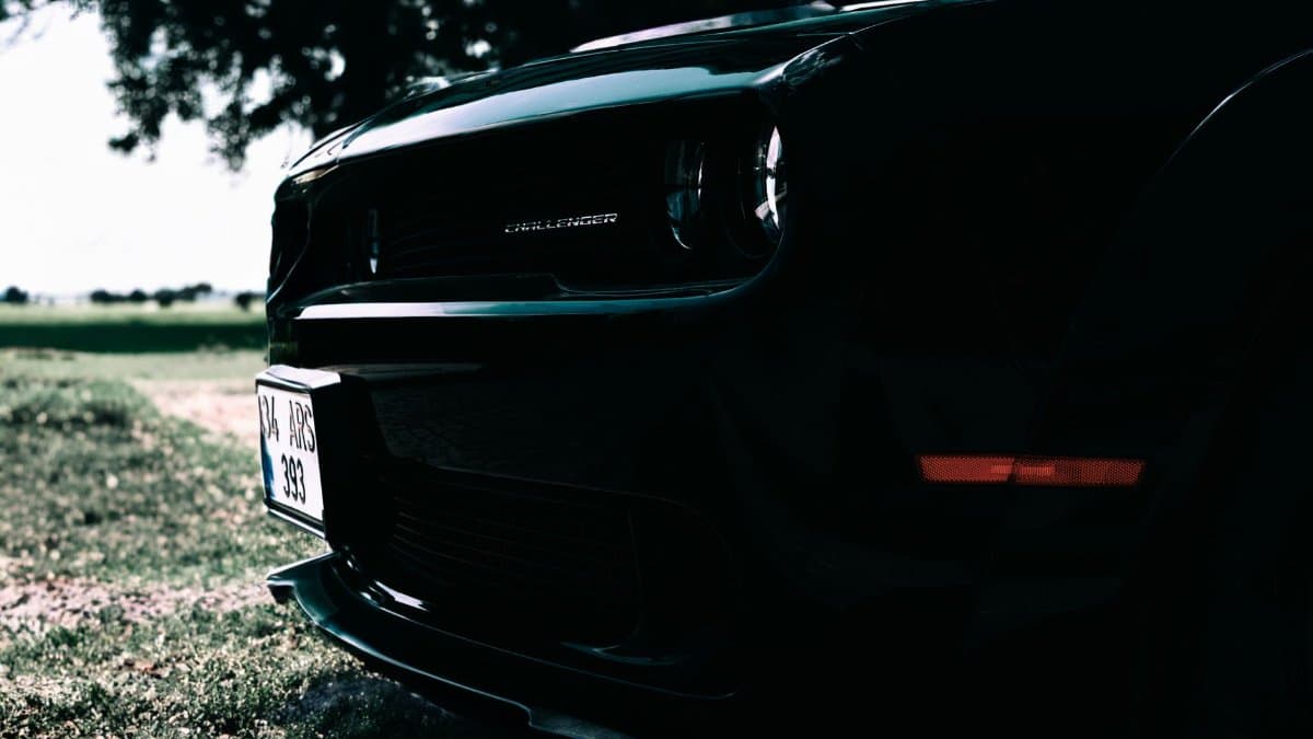 Low-angle view of a sleek Dodge Challenger highlighting its front details against a sunny backdrop.