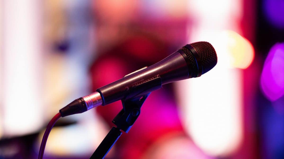 Close-up shot of a microphone on stage with colorful background bokeh, capturing live performance ambiance.
