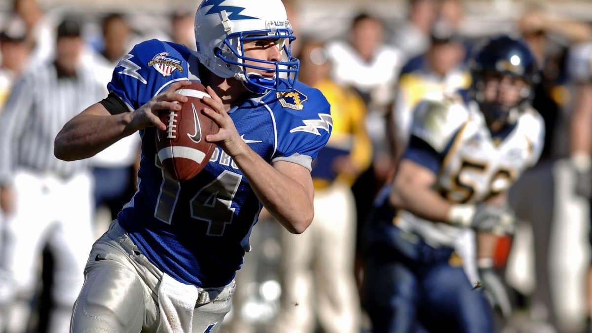 Player in blue jersey focuses on passing during a competitive football game.