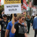 Group of protesters with placards supporting Writers Guild on a street demonstration.