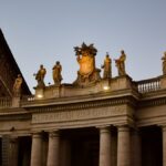 Elevated view of St. Peter's Basilica facade at dusk showcasing statues under a twilight sky.