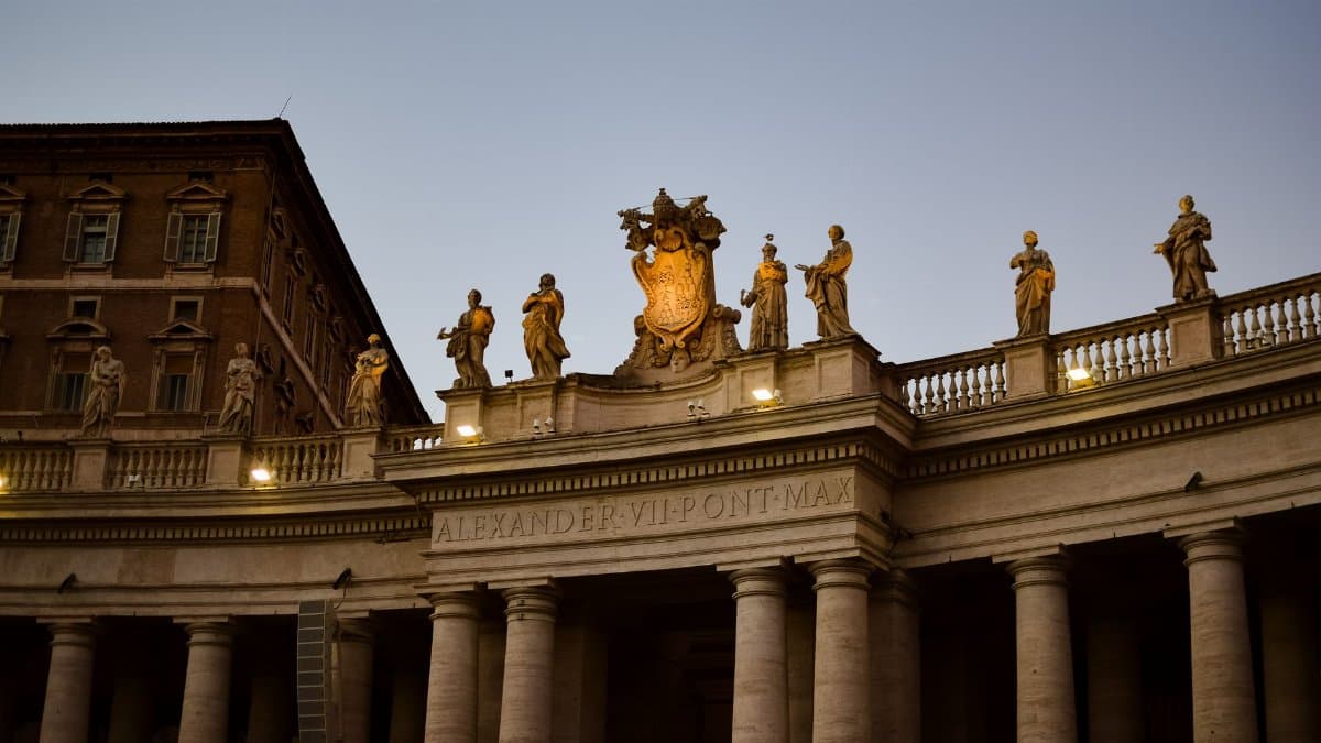 Elevated view of St. Peter's Basilica facade at dusk showcasing statues under a twilight sky.