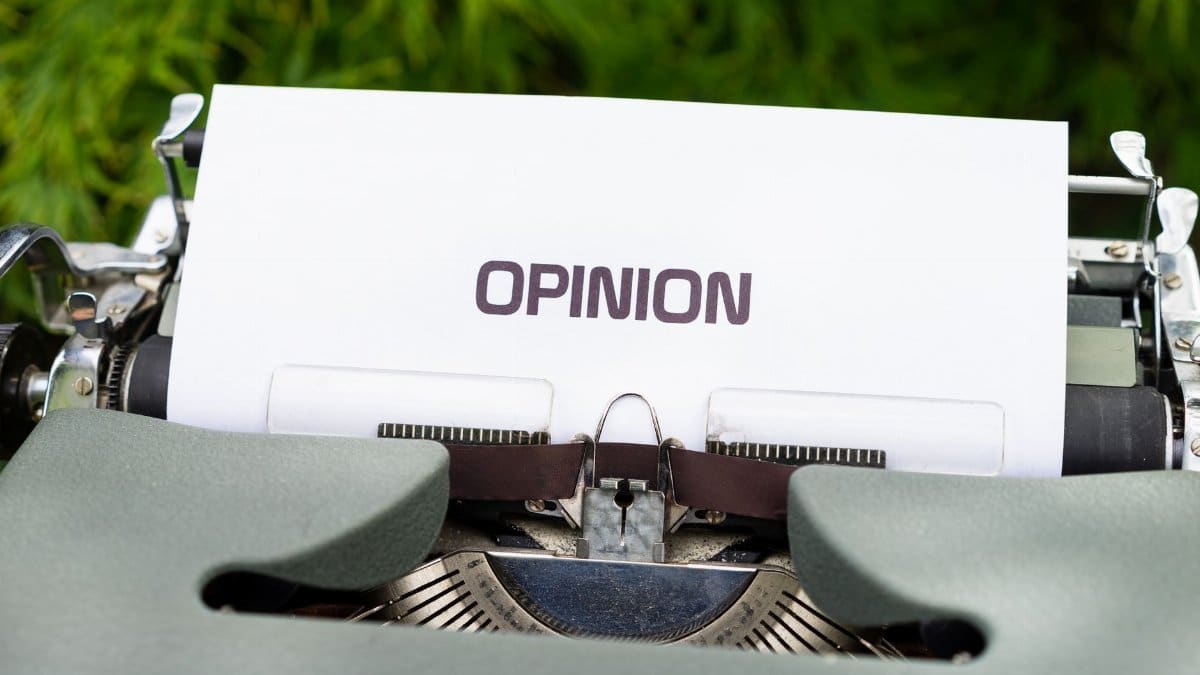 Close-up of a typewriter with paper showing the word 'Opinion' outdoors.