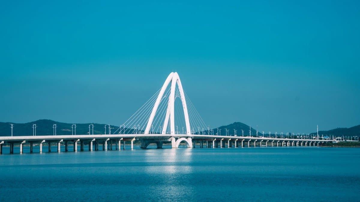 A contemporary cable-stayed bridge spanning serene blue water under clear skies.