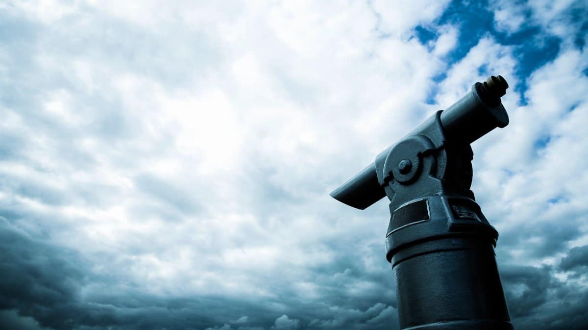 A close-up view of a coin-operated telescope pointing towards a dramatic cloudy sky, capturing a sense of adventure.