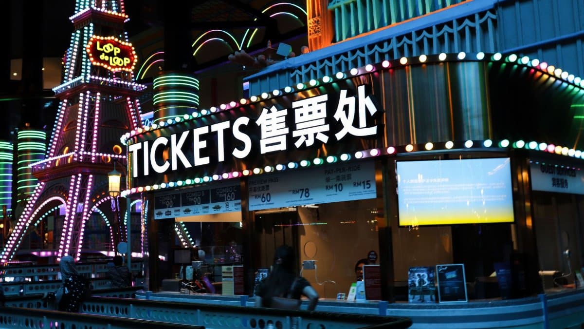 Illuminated ticket booth with vibrant neon lights at night, featuring colorful signage.