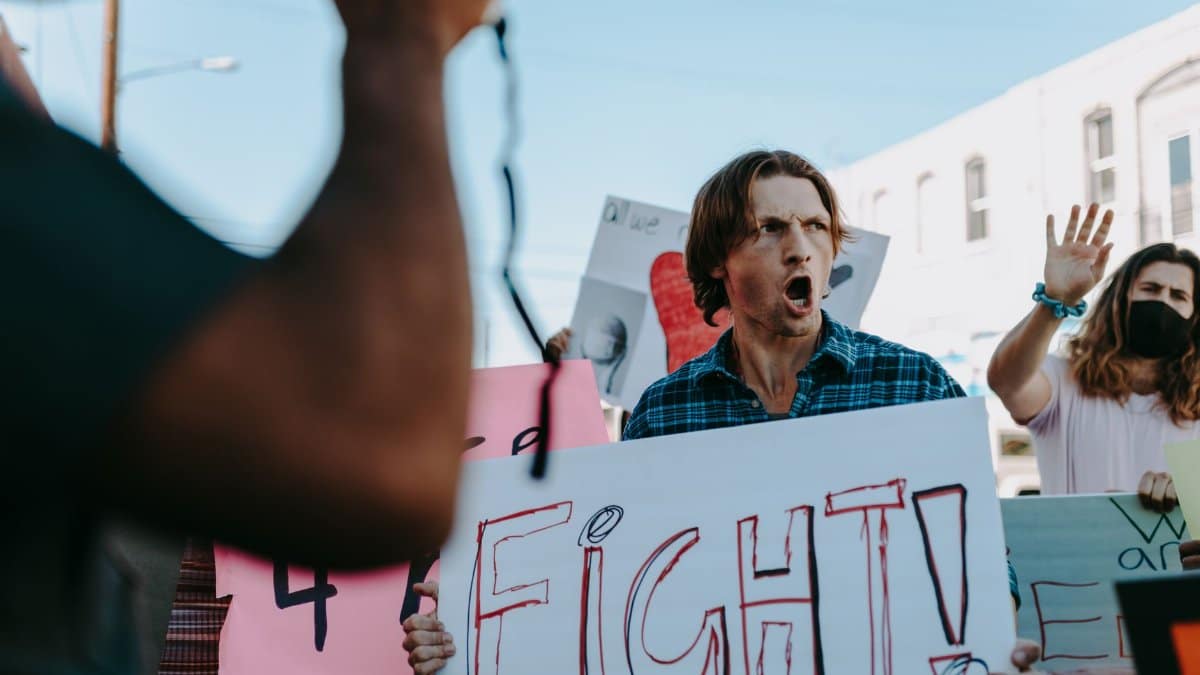 A passionate protester shouts and holds a sign during a public demonstration.