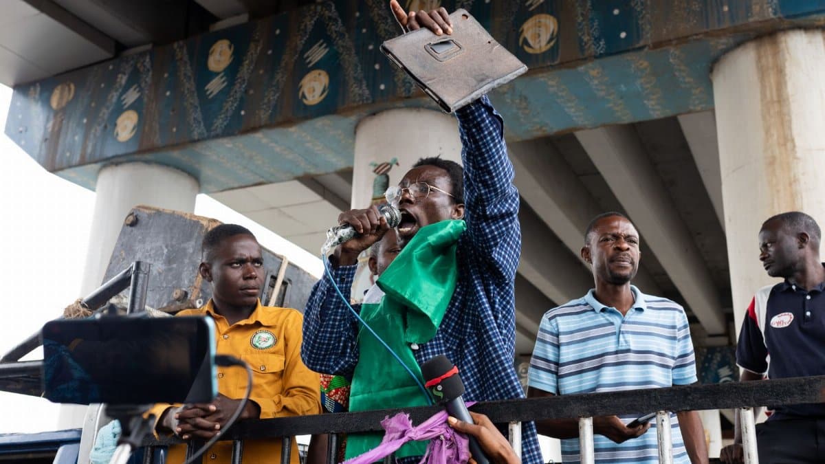 A group of men during a peaceful protest, one holding a microphone and banner.
