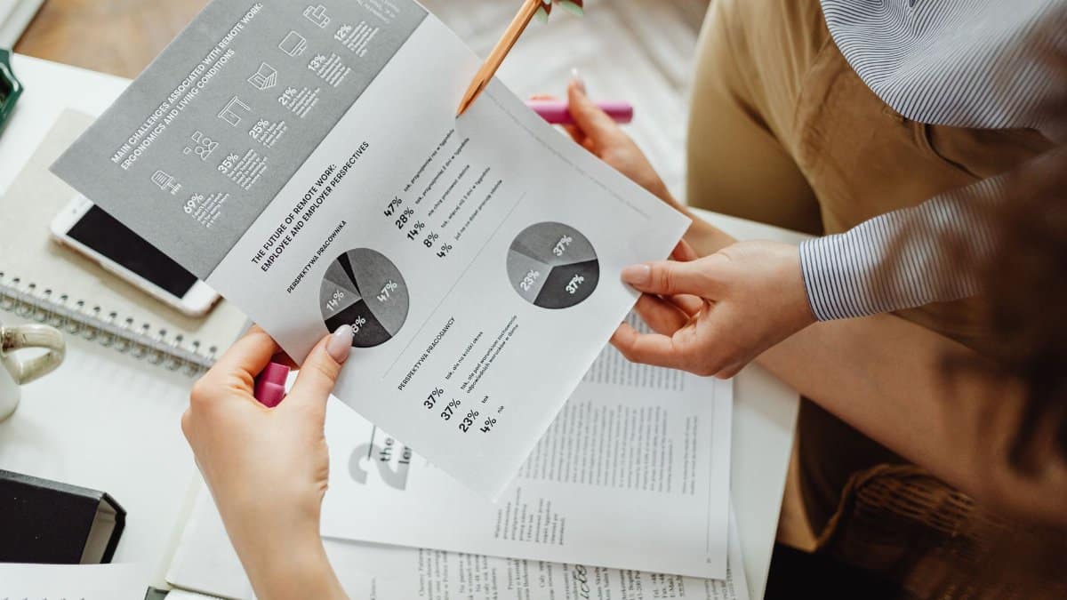Two people reviewing financial reports and graphs at a desk for analysis and decision-making.