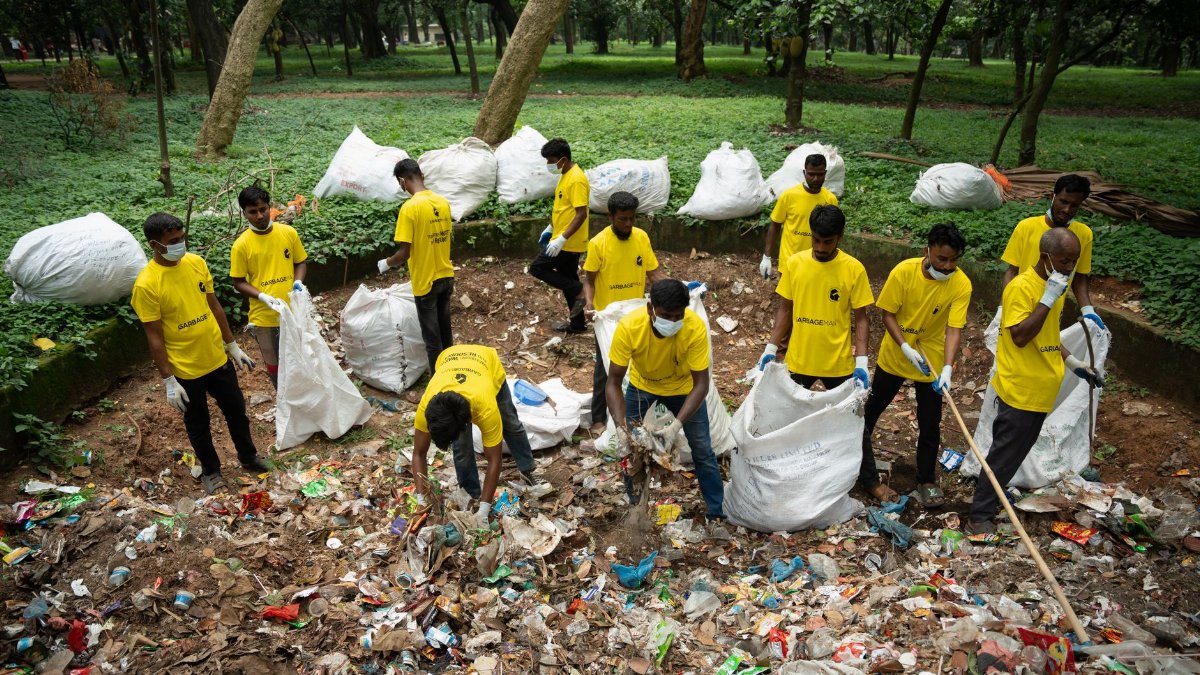 A group of volunteers in yellow shirts cleaning litter in a park, promoting environmental awareness.