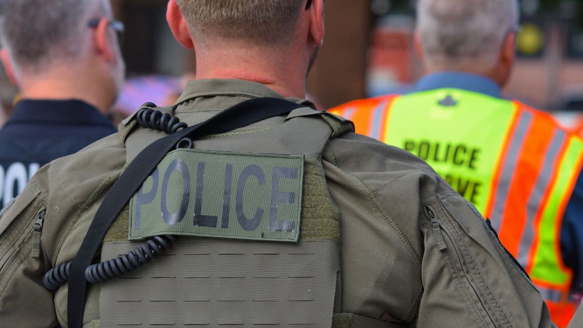 Rear view of police officers in tactical gear and high-visibility vests in a public setting.