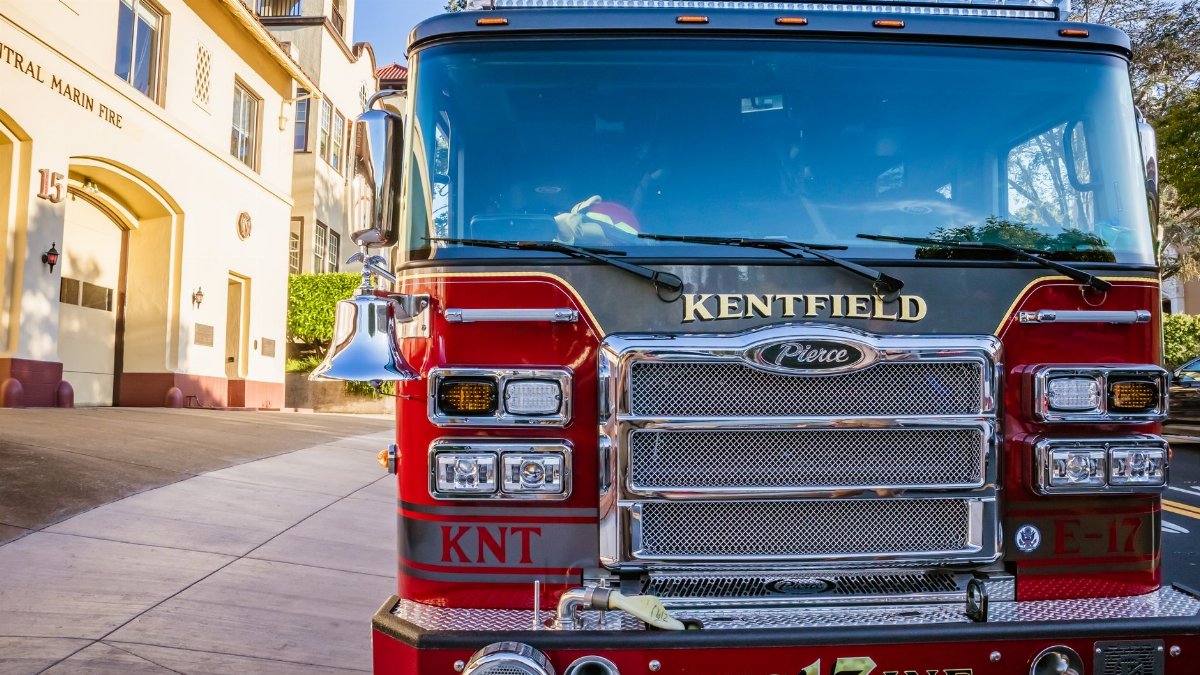 Front view of a red fire truck parked in front of Central Marin Fire Station on a sunny day.