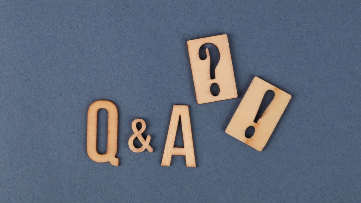 Flat lay of wooden Q&A letters with punctuation marks on a gray background.