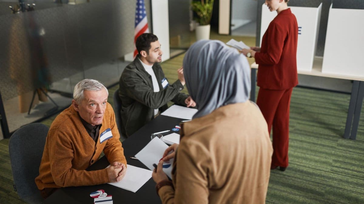 Adults engaging in the voting process at an indoor polling station, representing diverse backgrounds and social responsibility.
