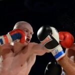Two male boxers in mid-action during a competitive fight, showcasing strength and agility.