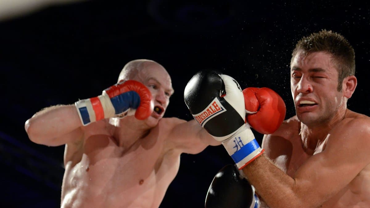 Two male boxers in mid-action during a competitive fight, showcasing strength and agility.