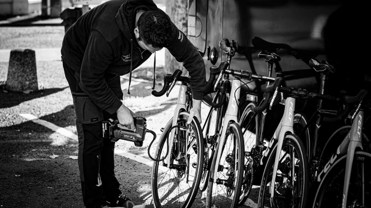 A man in a hoodie examining a row of road bicycles outdoors.
