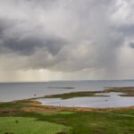 A dramatic scene of a coastal landscape with storm clouds and a serene horizon over the ocean.