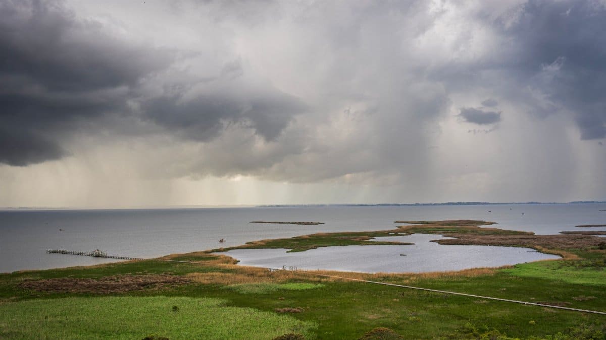 A dramatic scene of a coastal landscape with storm clouds and a serene horizon over the ocean.