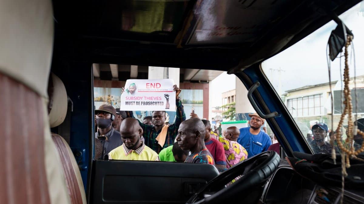 A group of protesters gathered outside a vehicle holding signs during a city protest.