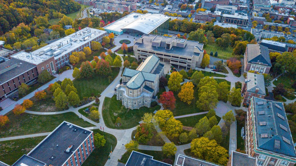 Drone shot capturing a scenic university campus with vibrant fall foliage.