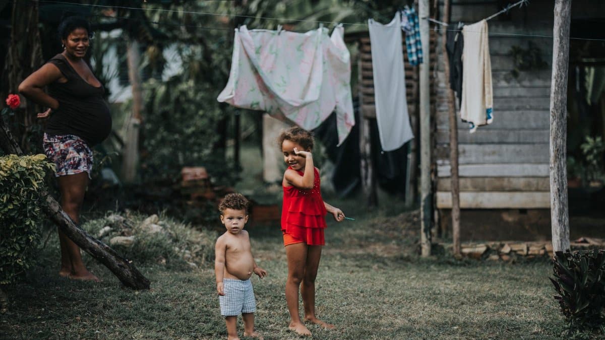 Joyful children playing outdoors in a Cuban yard with clothes hanging in the background.