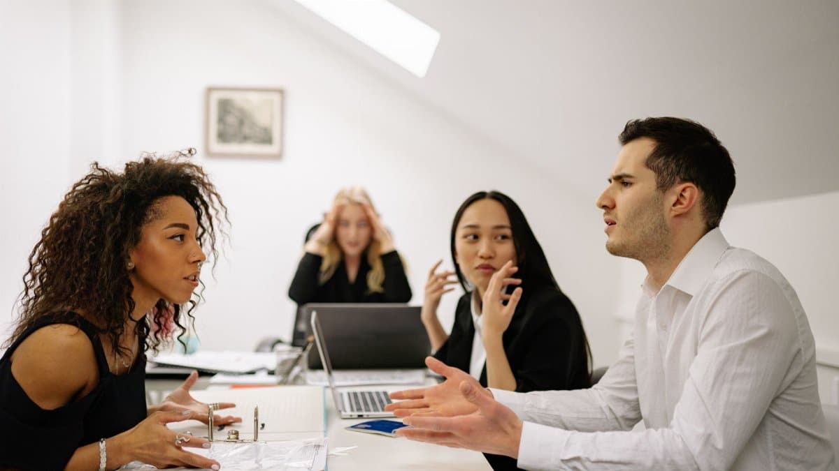 A multi-ethnic team engaged in a heated office discussion, displaying various emotions.