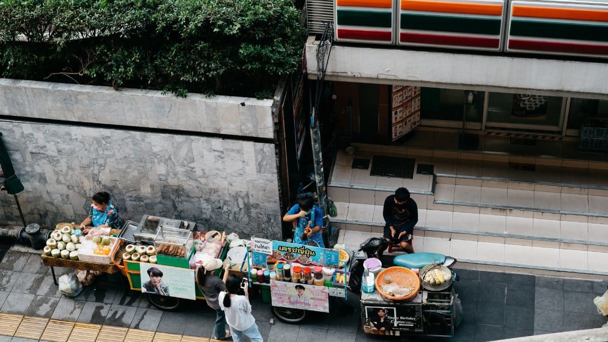 Vibrant street scene showing local vendors selling food from carts on a bustling city sidewalk.