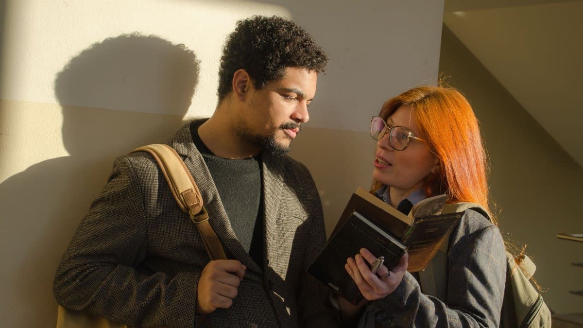 Two university students engaged in a discussion while reading a book inside a building in Buenos Aires, Argentina.