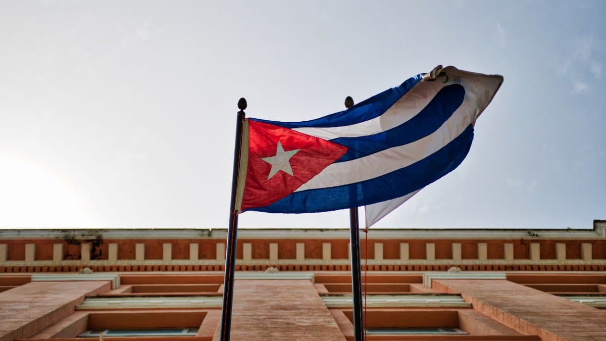 Cuban flag waving against a historic building in Havana, capturing national pride and architectural beauty.