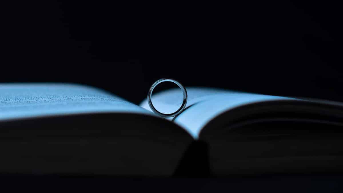 A dramatic close-up shot of a ring casting a shadow on an open book, symbolizing reading and romance.