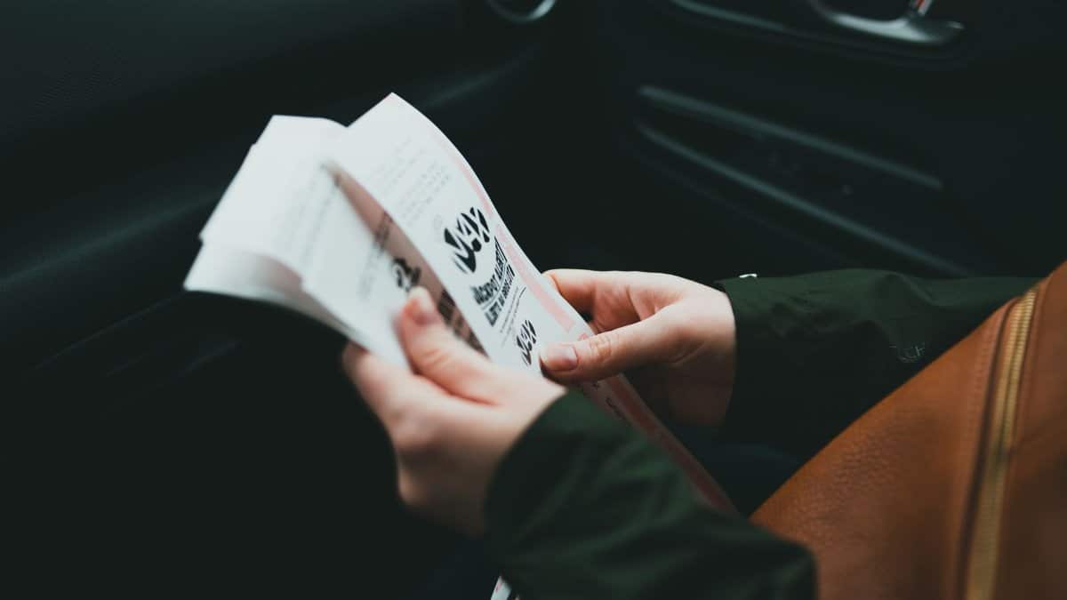 Close-up of hands holding a brochure inside a car, creating an intimate and focused scene.